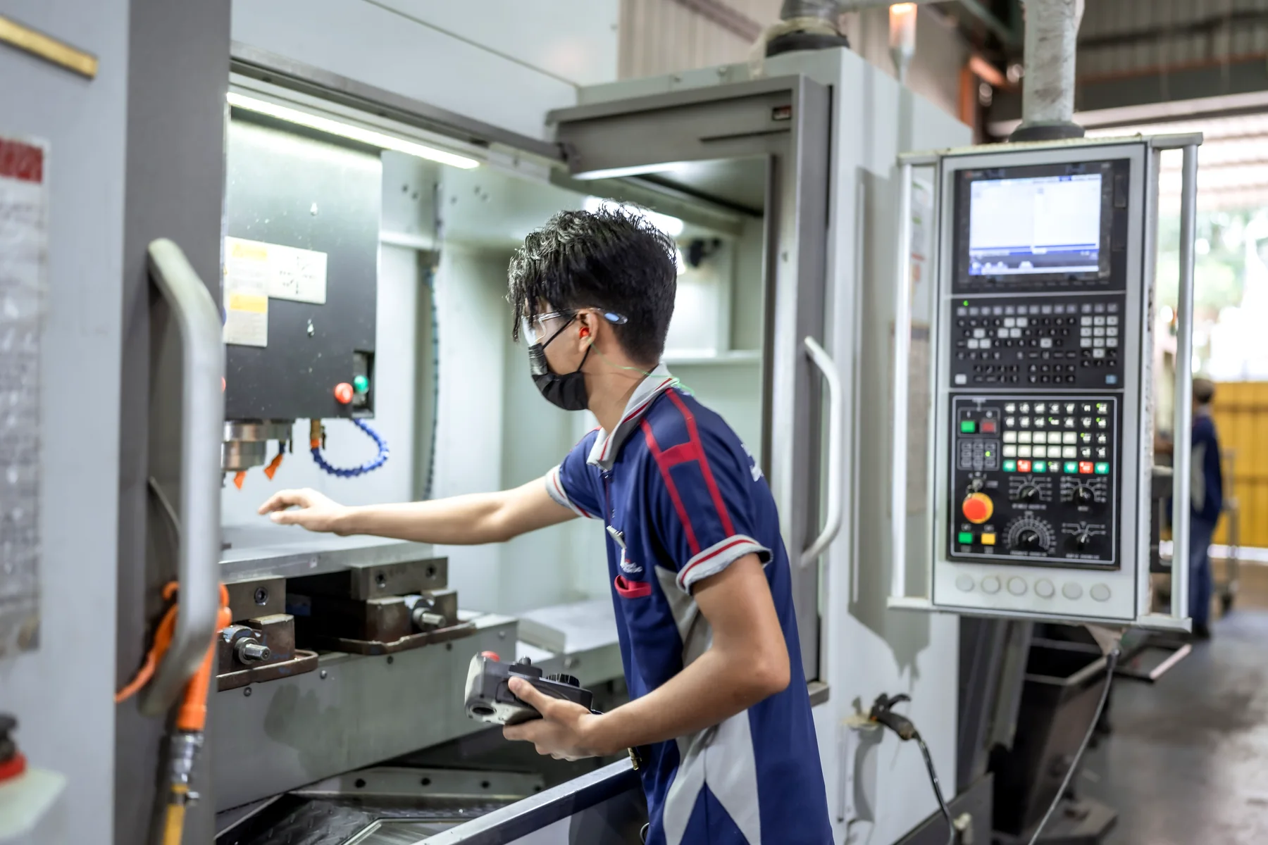 A Yong Heng machinist loading work into a CNC machining centre.
