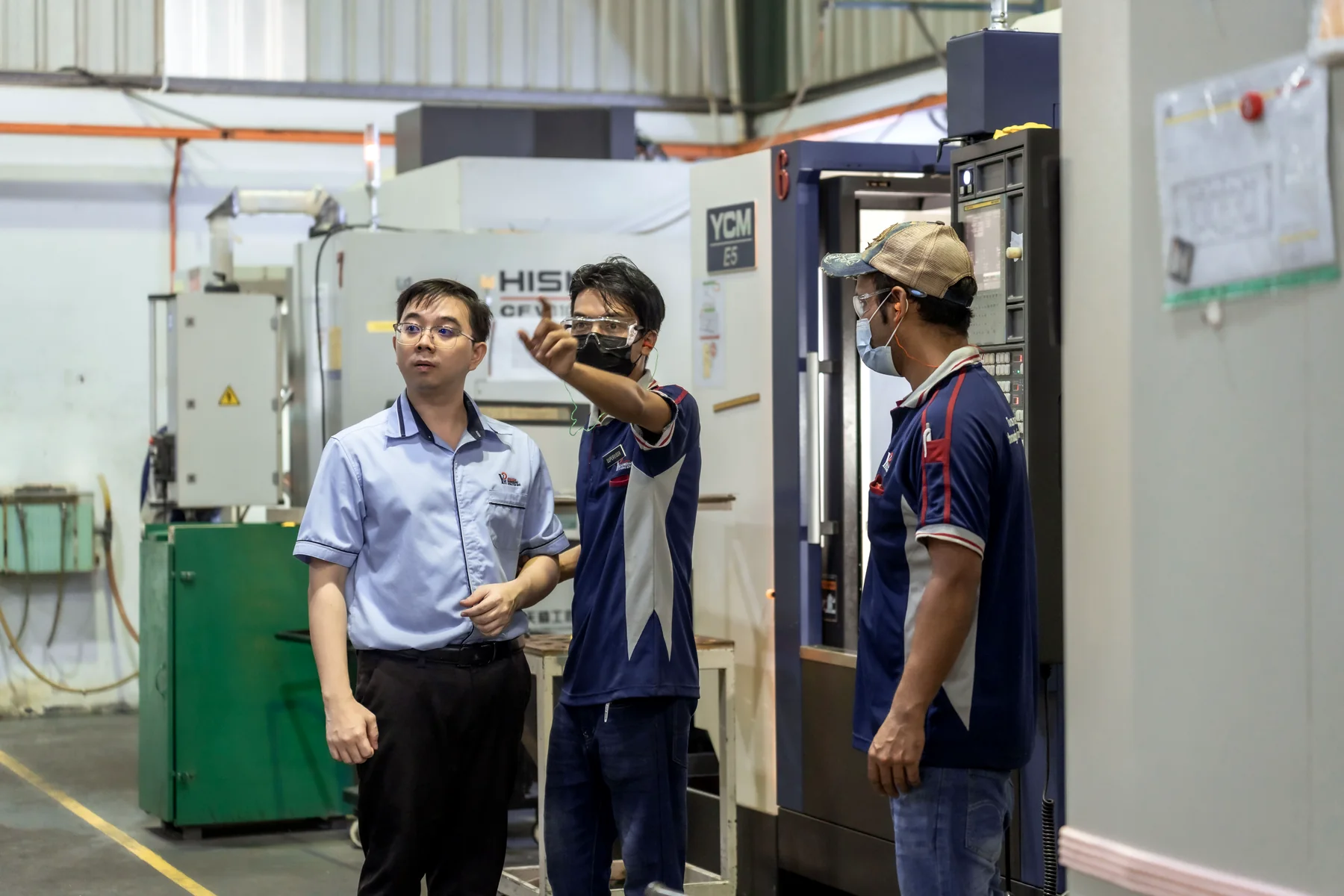 Yong Heng engineers discussing a job at a machine.